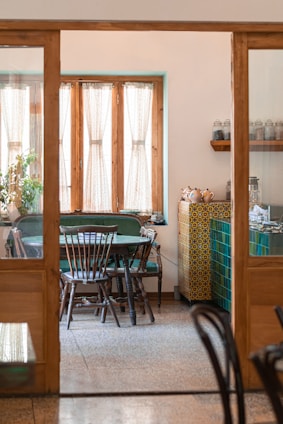 A warm, sunlit dining area with rustic wooden tables and vibrant spice jars on shelves.