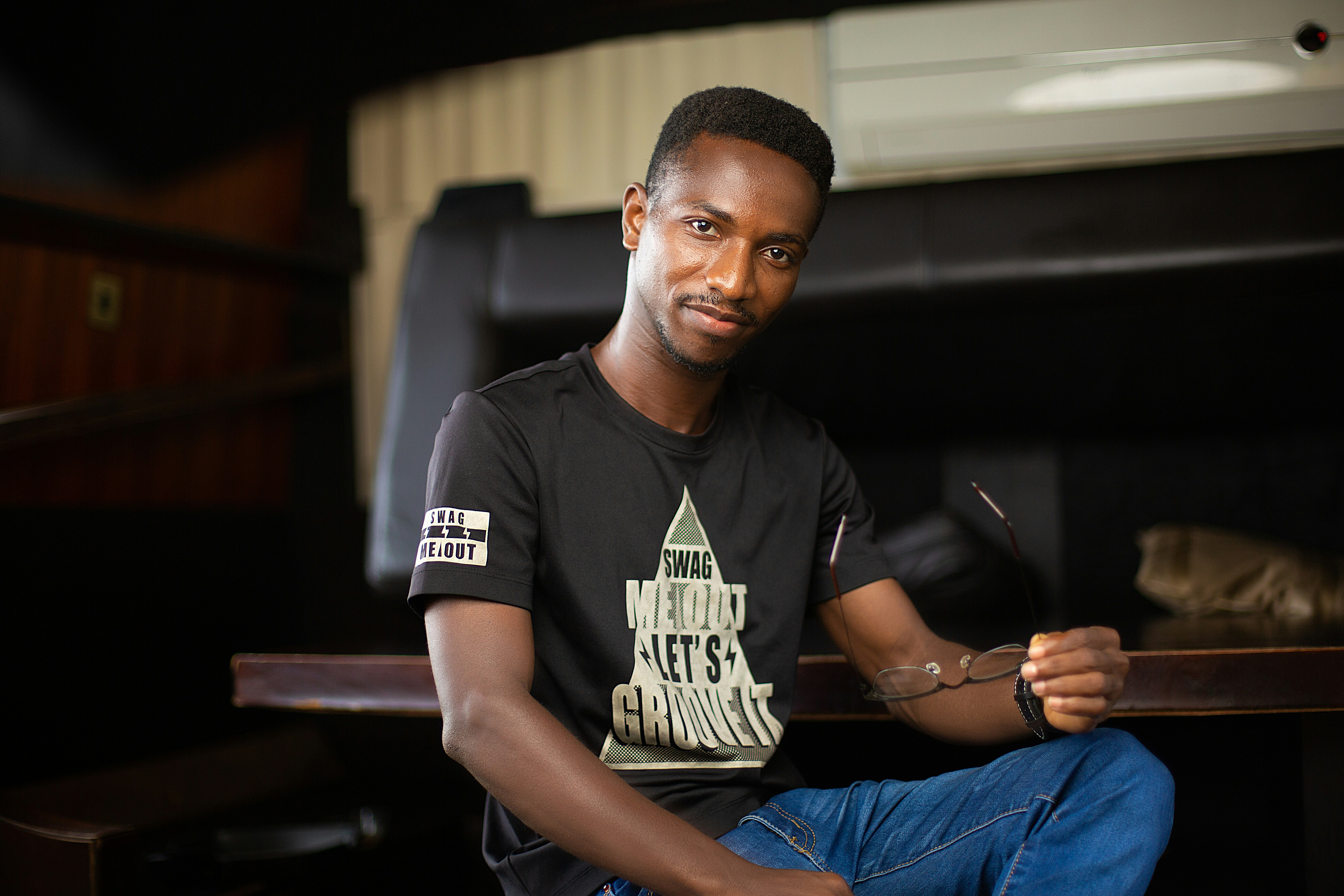 man in black crew neck t-shirt and blue denim jeans sitting on black chair