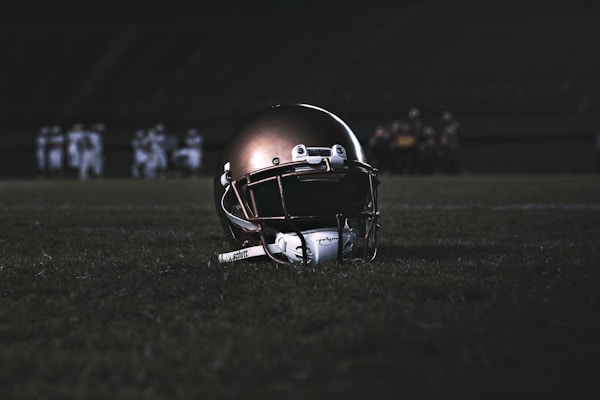 football helmet on green grass field during night timeby Lucas Andrade
