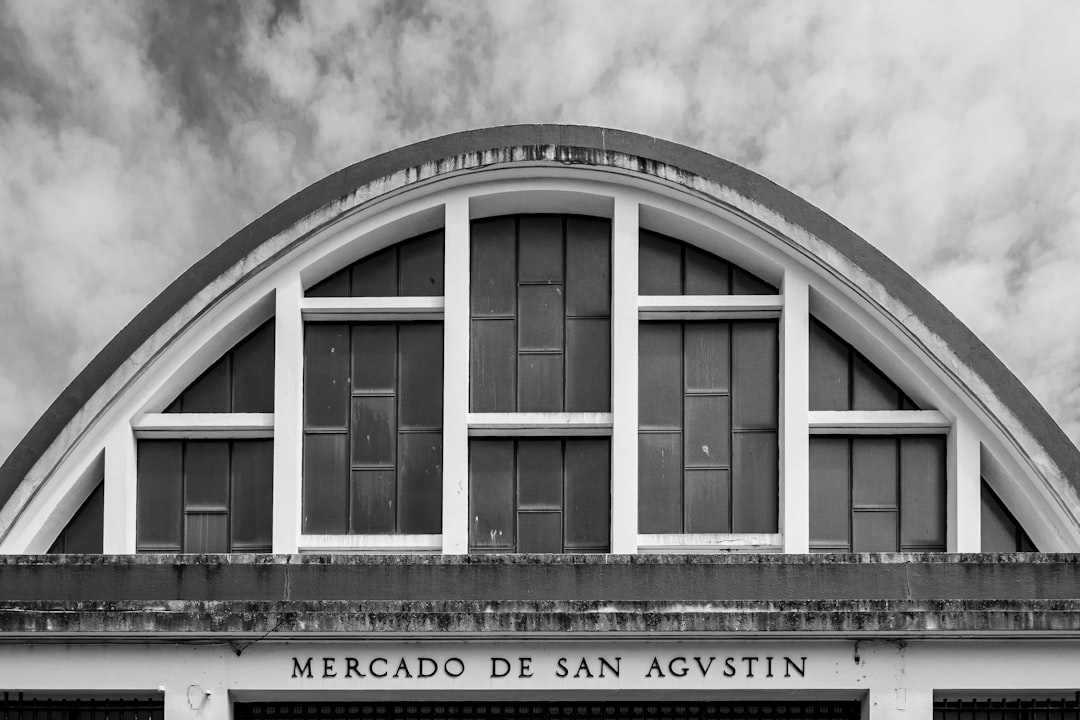 grayscale photo of building under cloudy sky