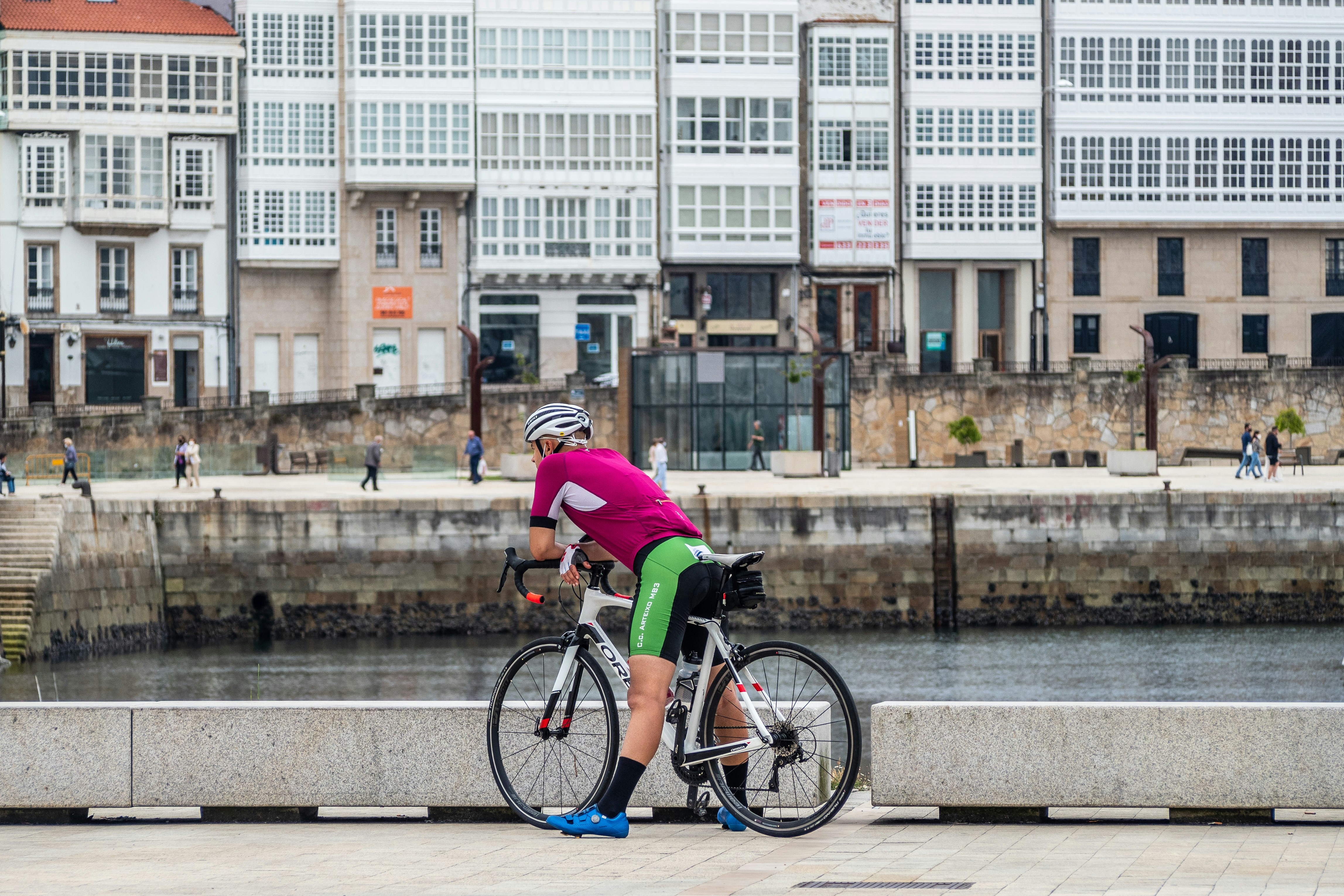 man in green shirt riding on bicycle near body of water during daytime