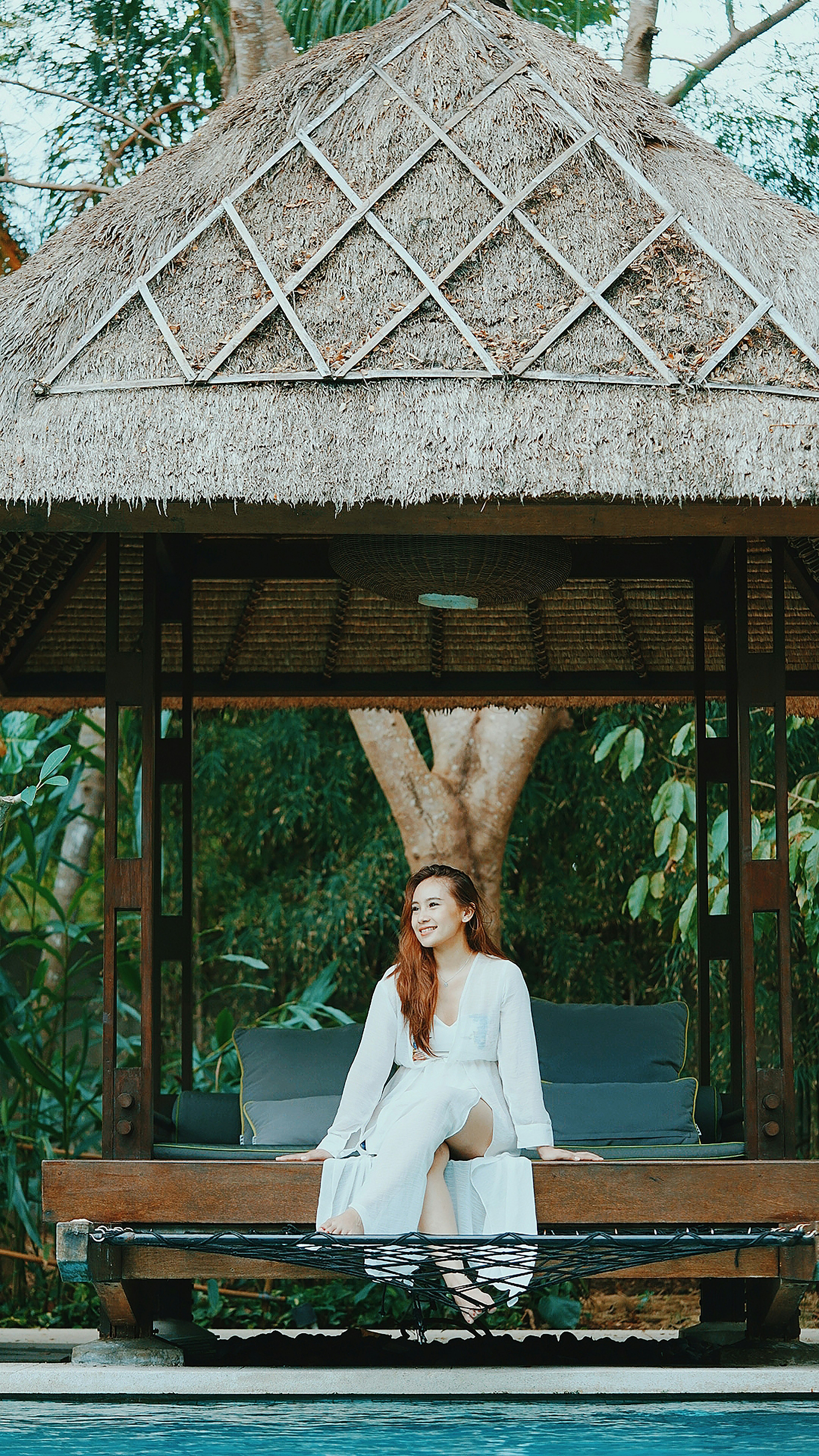 woman in white blazer standing under brown wooden roof