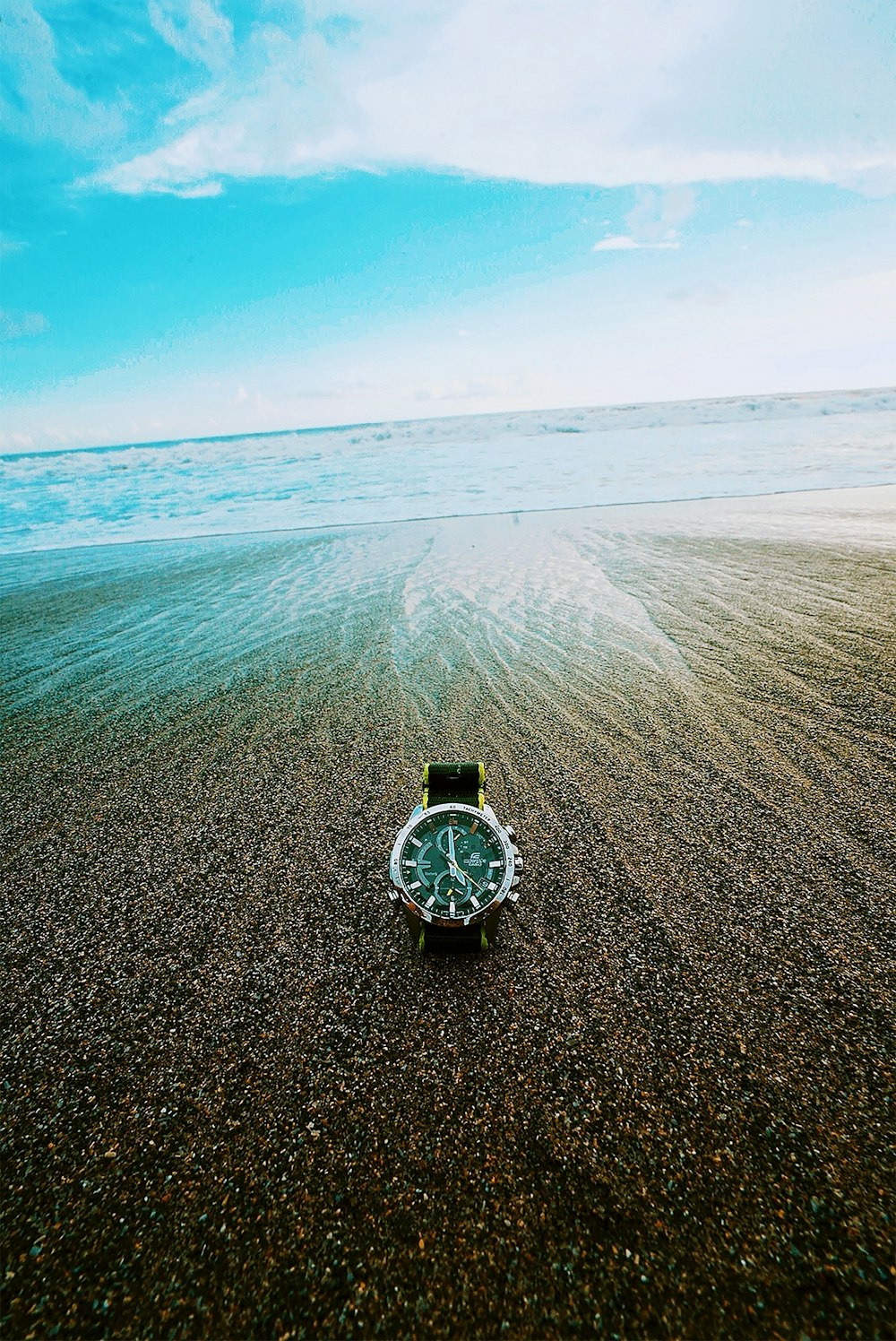 silver round analog watch on beach