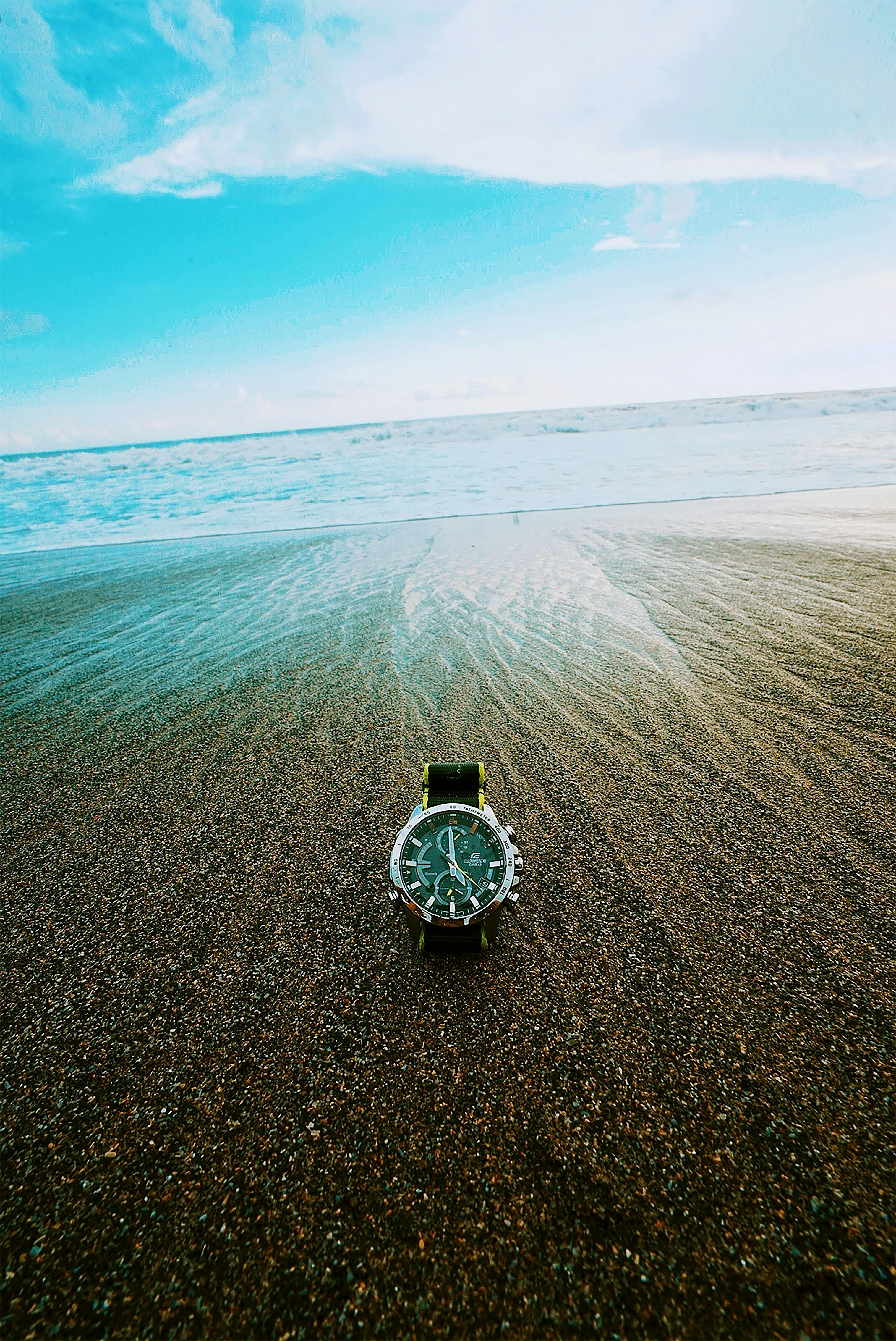 silver round analog watch on beach