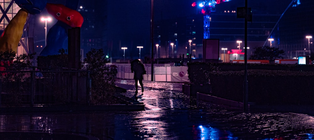 man in black jacket walking on sidewalk during night time