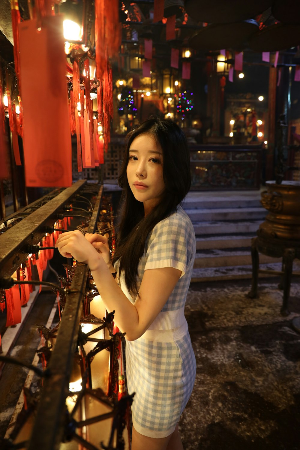 woman in white and blue plaid dress shirt holding a glass bottle