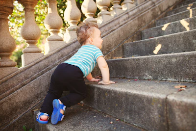 boy in green and white striped t-shirt and black pants sitting on concrete stairs during
