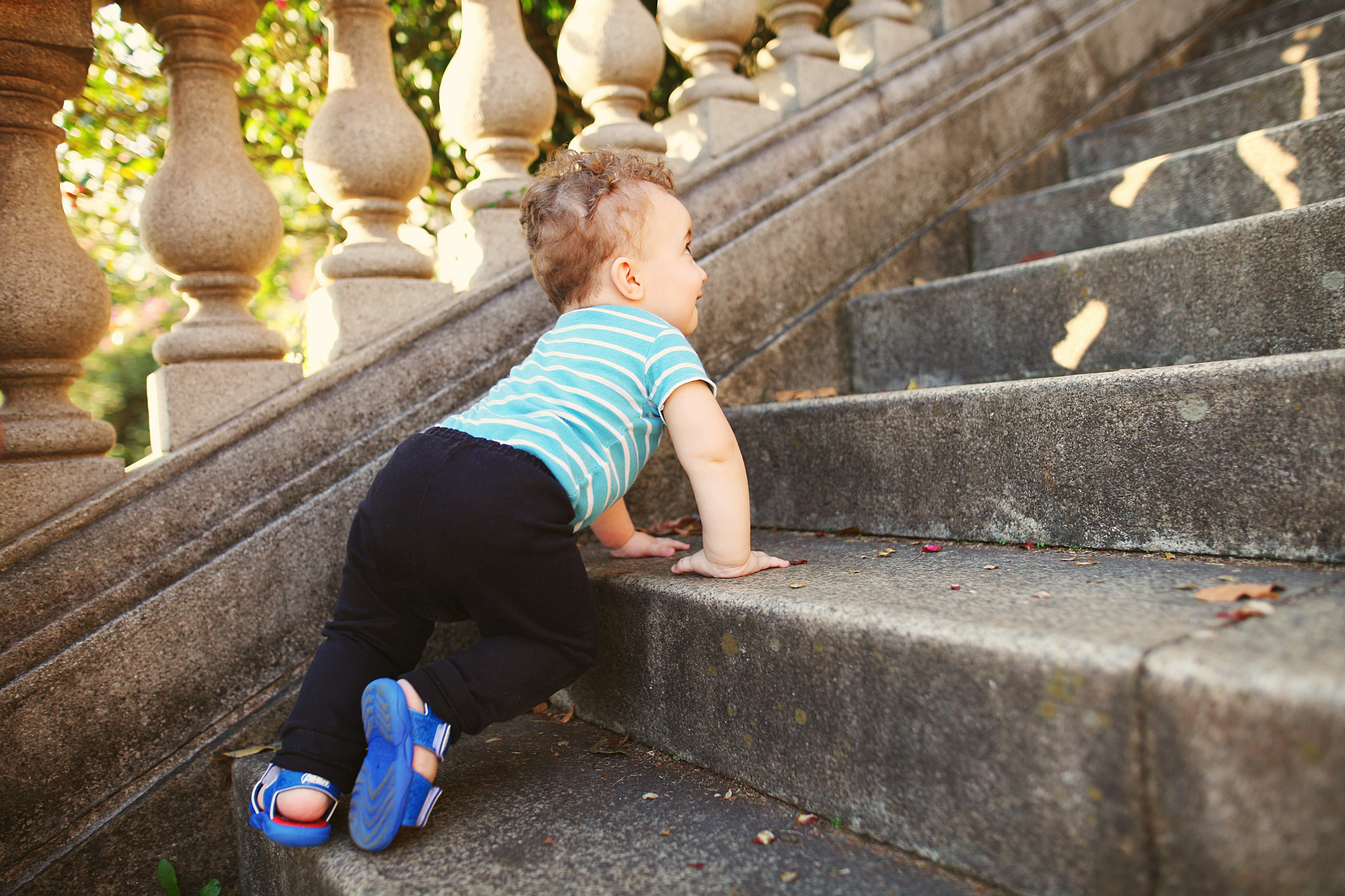 boy in green and white striped t-shirt and black pants sitting on concrete stairs during