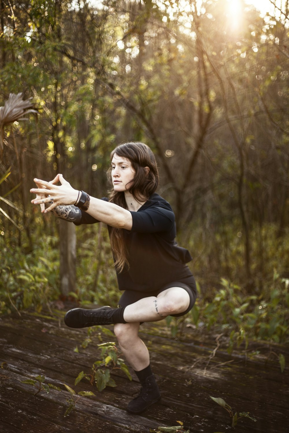 woman in black long sleeve shirt and brown pants sitting on brown wooden log during daytime