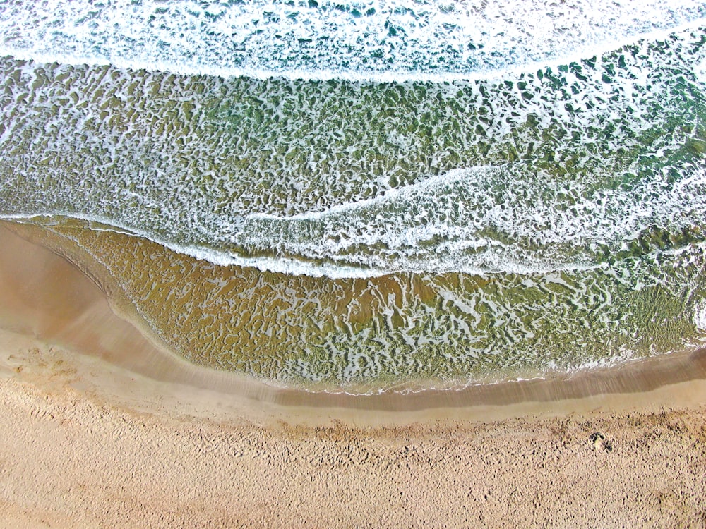 an aerial view of a beach with waves and sand