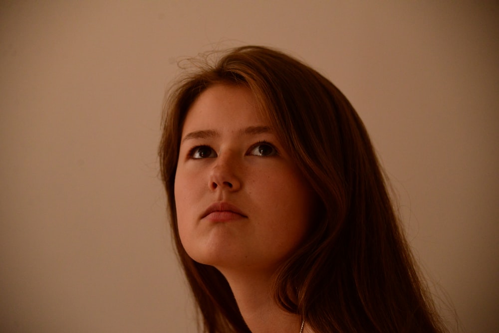 a woman with long hair looking up at something