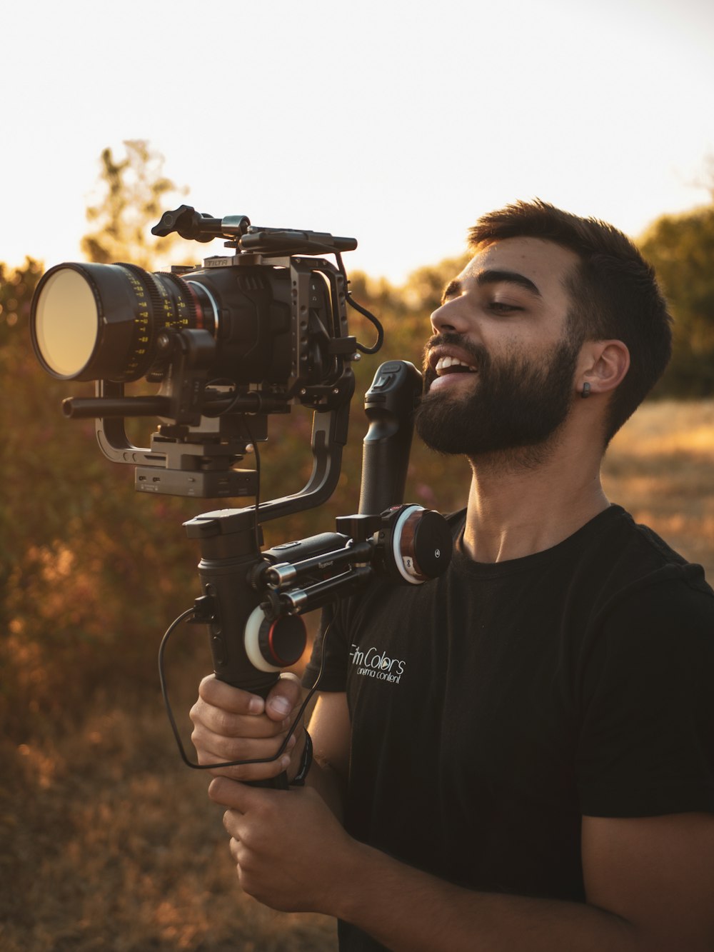 man in black crew neck t-shirt holding black dslr camera during daytime