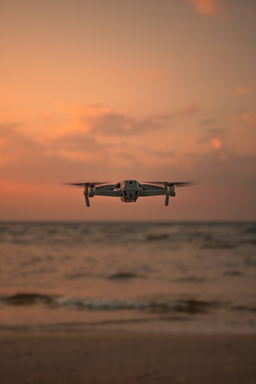 black and white drone flying over the sea during sunset
