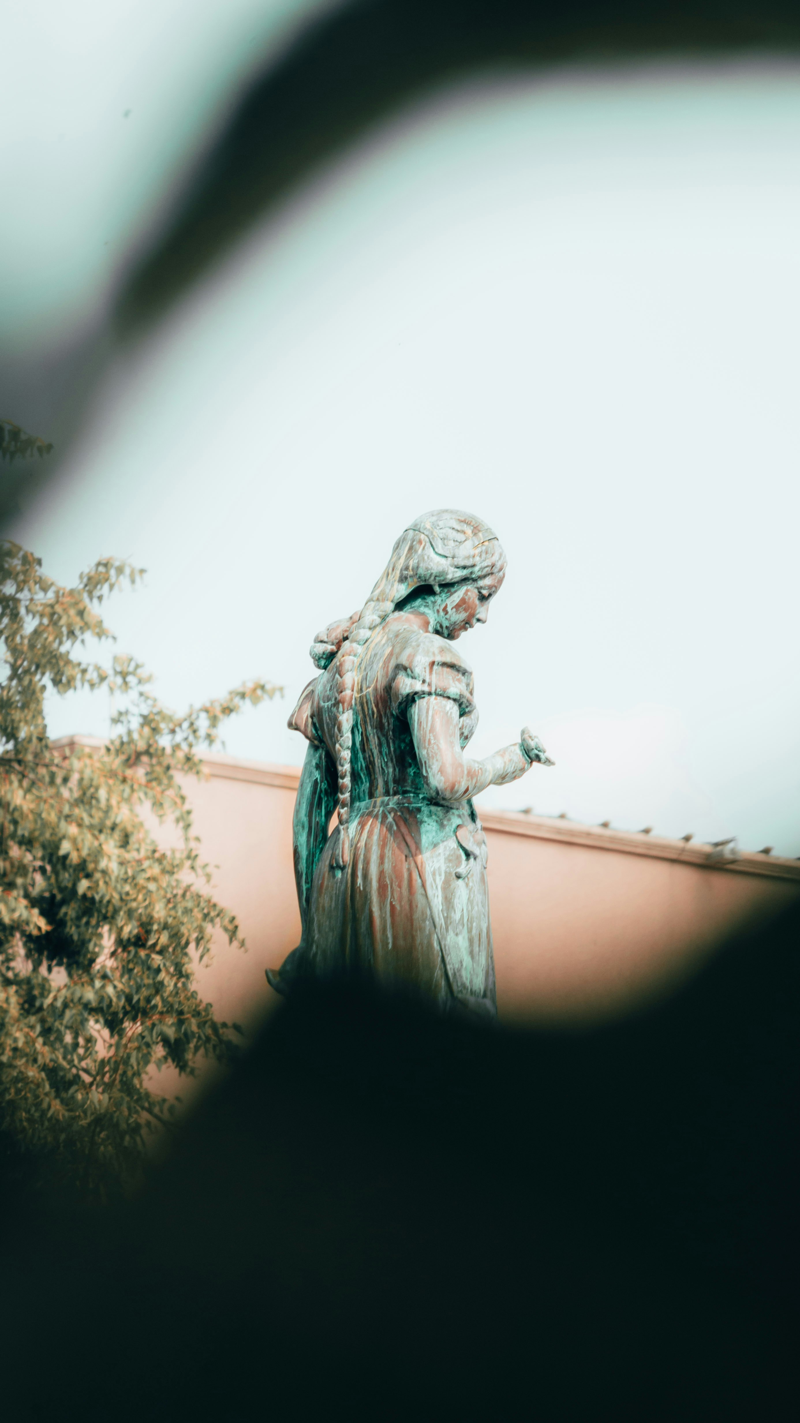 woman in dress statue near green trees during daytime