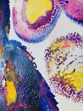 An abstract painting featuring swirling patterns of textured paint. Bright colors such as yellow, purple, and blue dominate the composition. The paint is applied in thick, expressive strokes, creating a dynamic and energetic visual effect.