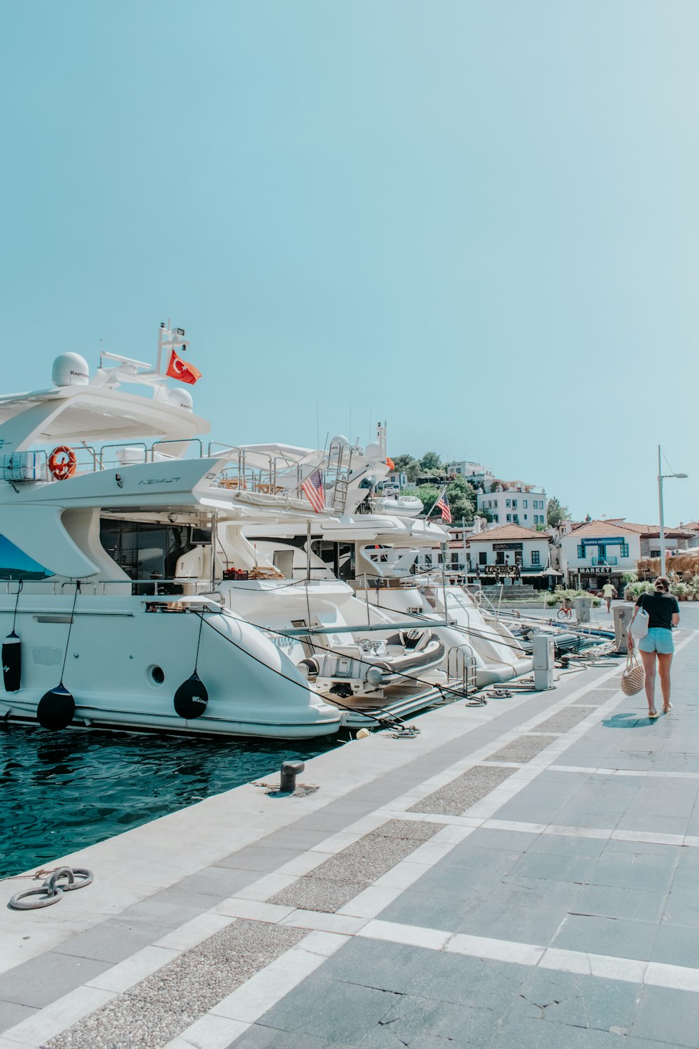 people walking on sidewalk near white yacht during daytime