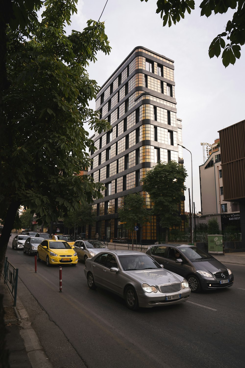 cars parked on side of road near high rise building during daytime