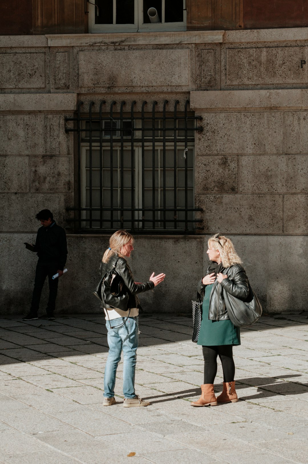 woman in black jacket and blue denim jeans standing beside woman in gray coat