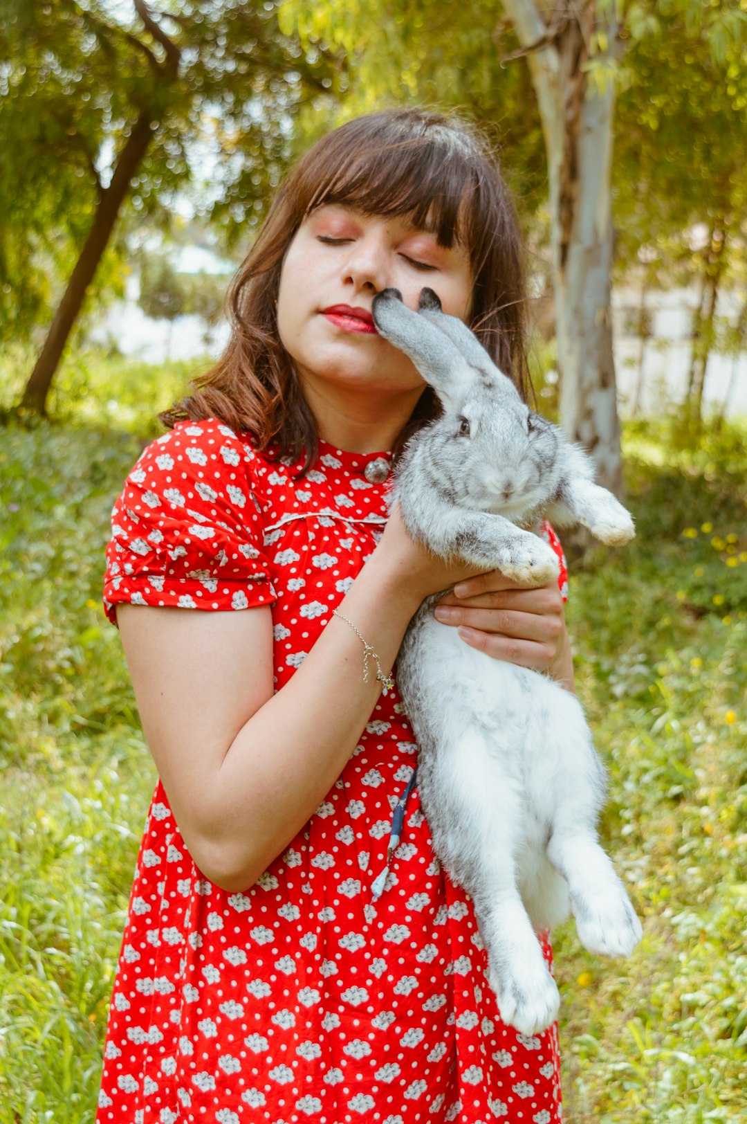 woman in red and white polka dot dress holding white rabbit