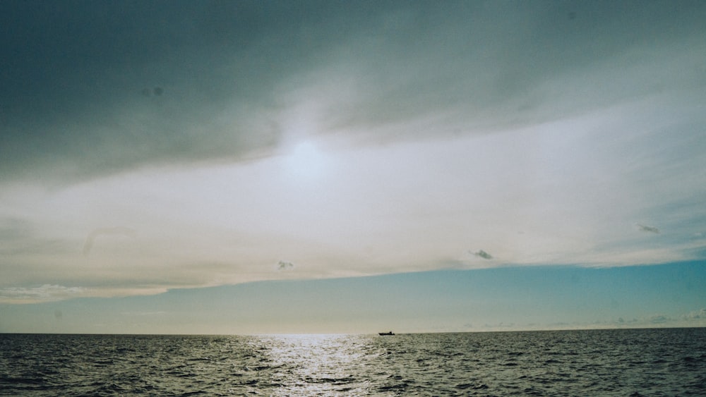 body of water under white clouds during daytime