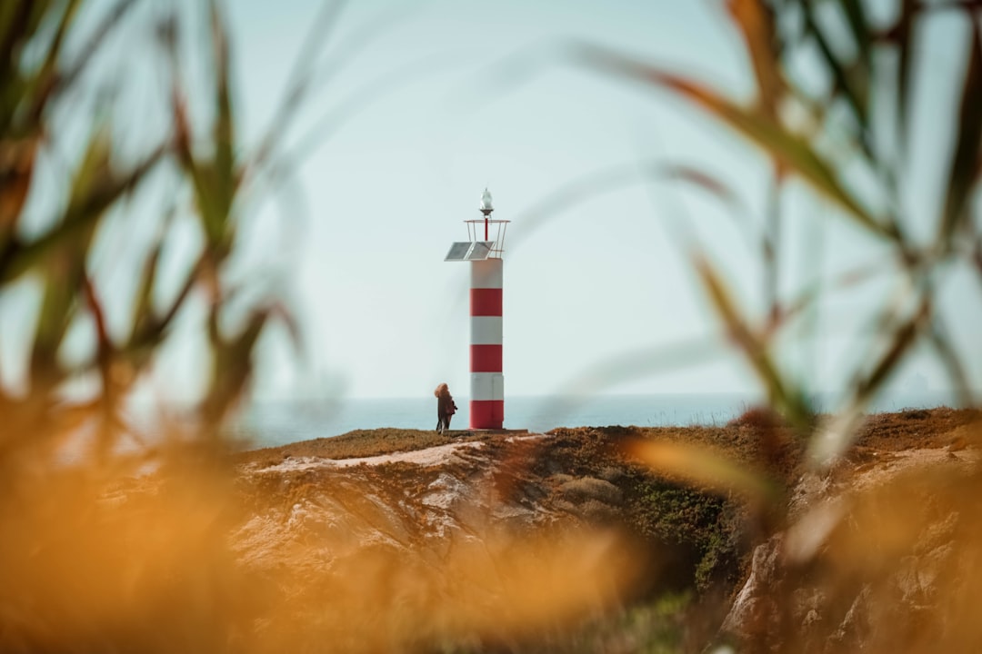 white and red lighthouse near body of water during daytime