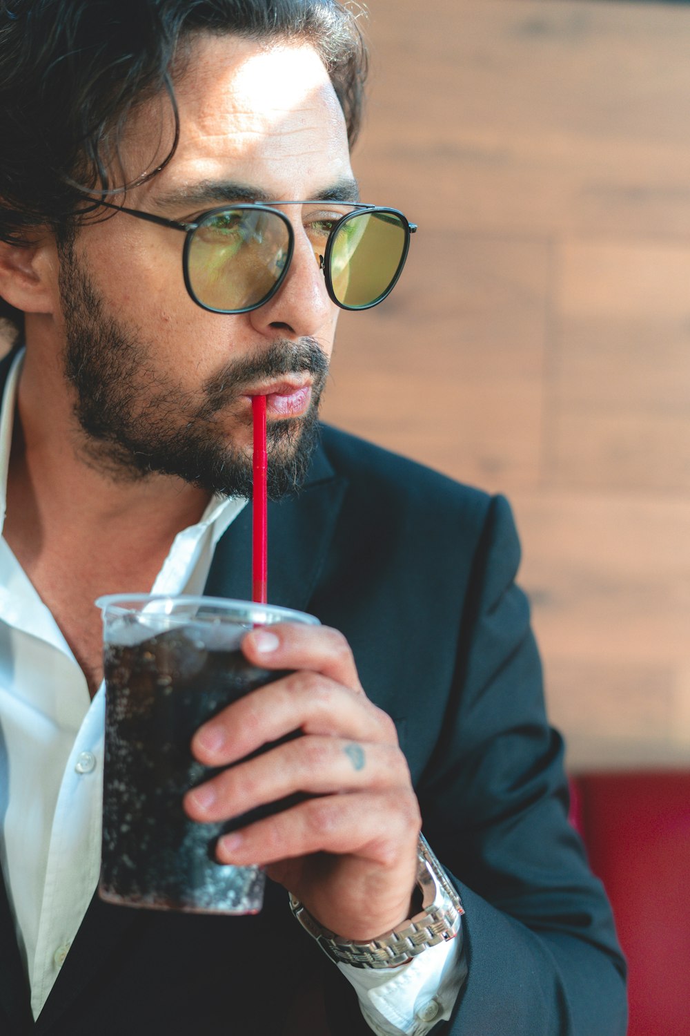 man in black suit holding clear drinking glass