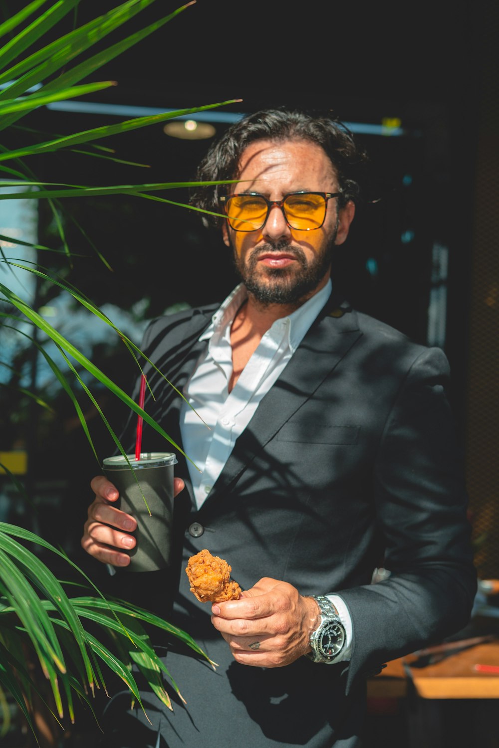 man in black suit holding glass cup