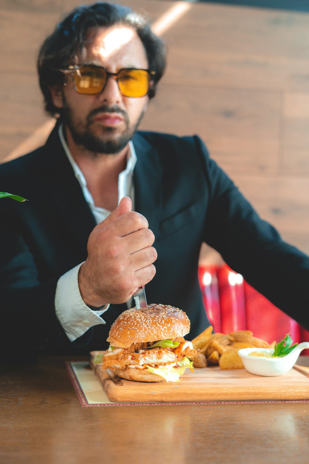 man in black suit jacket and white dress shirt holding burger