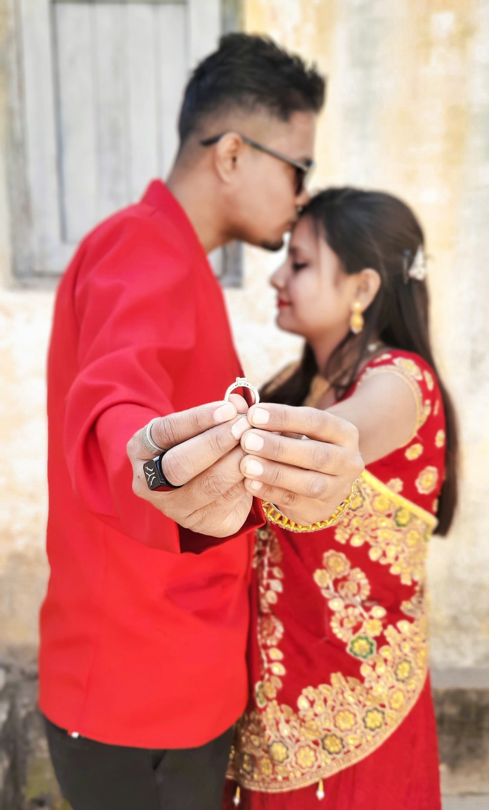 man in red robe kissing woman in red and yellow floral dress