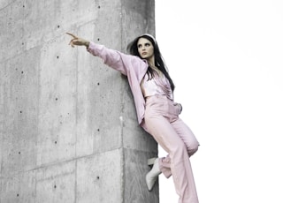 woman in pink coat standing on gray concrete wall