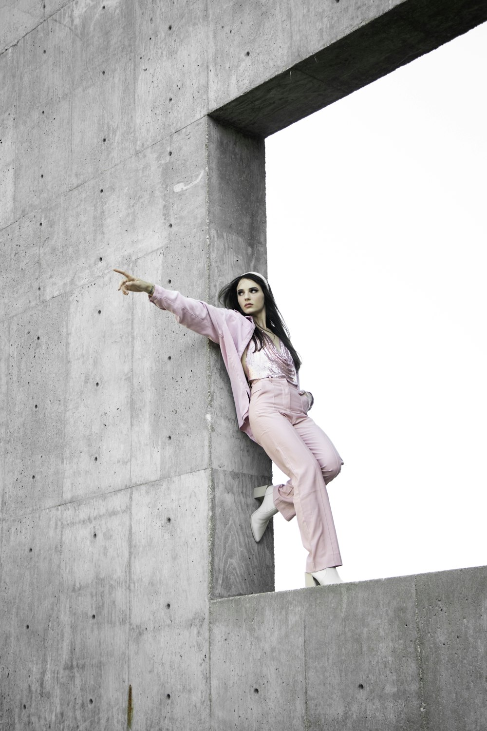 woman in pink coat standing on gray concrete wall