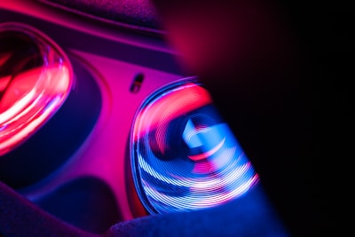 An abstract image featuring vibrant reflections of light in red, blue, and purple hues. The scene displays smooth, swirling patterns suggesting a sense of motion or energy. The shapes resemble the internal parts of an electronic device, possibly a headset.
