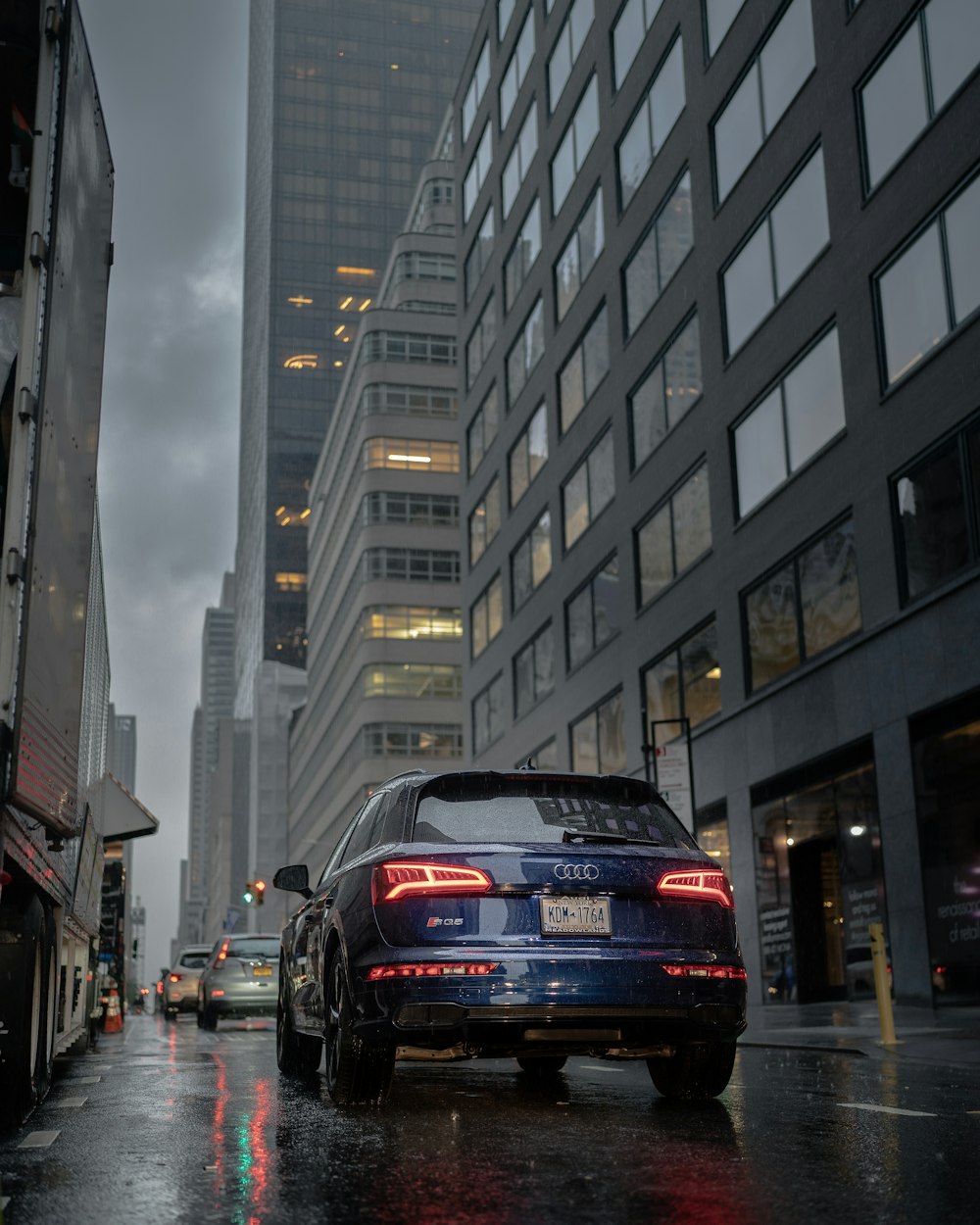 Audi A 4 negro en la carretera entre edificios de gran altura durante el día