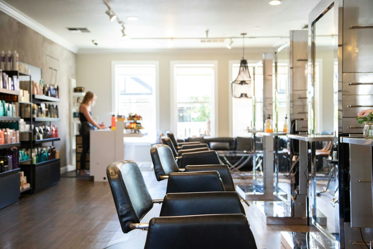 The Studio Mane floor: a row of black leather chairs facing the mirrors in daylight.