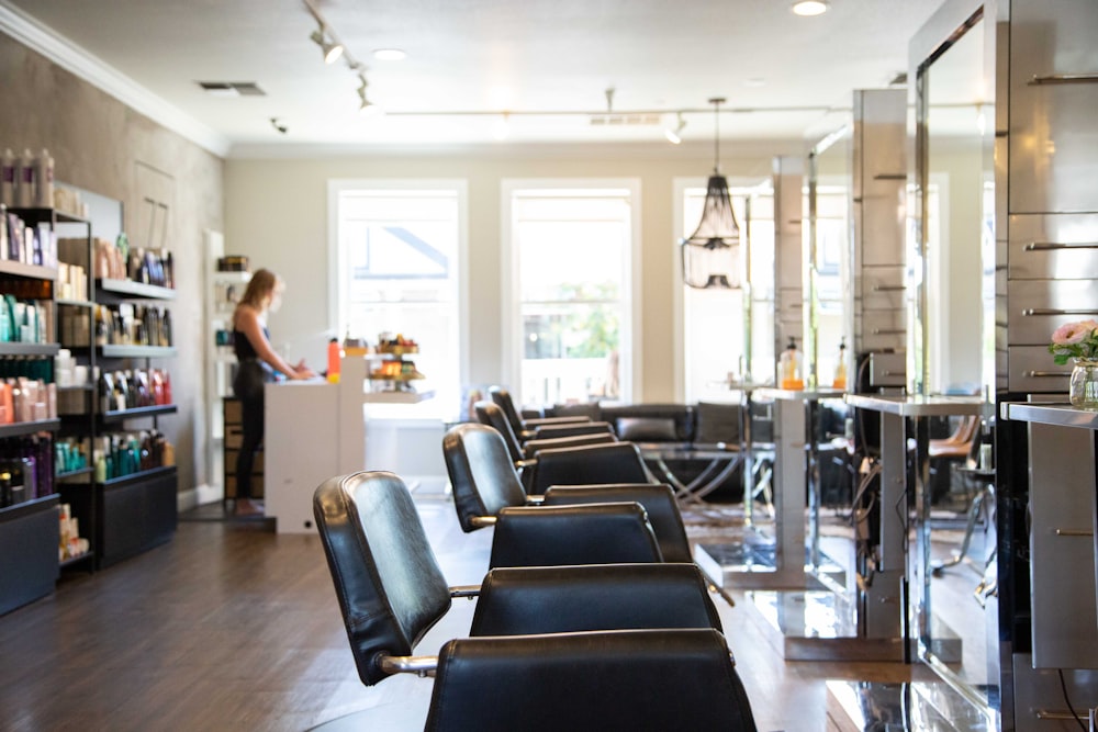 woman in white shirt standing near black leather chairs