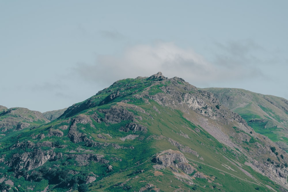 montagna verde e grigia sotto il cielo bianco durante il giorno