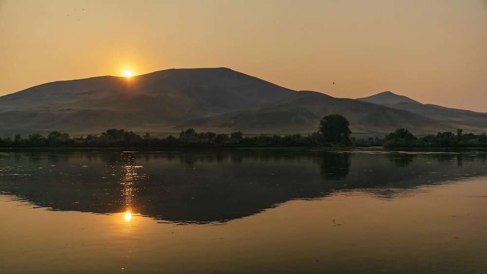 Silueta de la montaña cerca del cuerpo de agua durante la puesta del sol