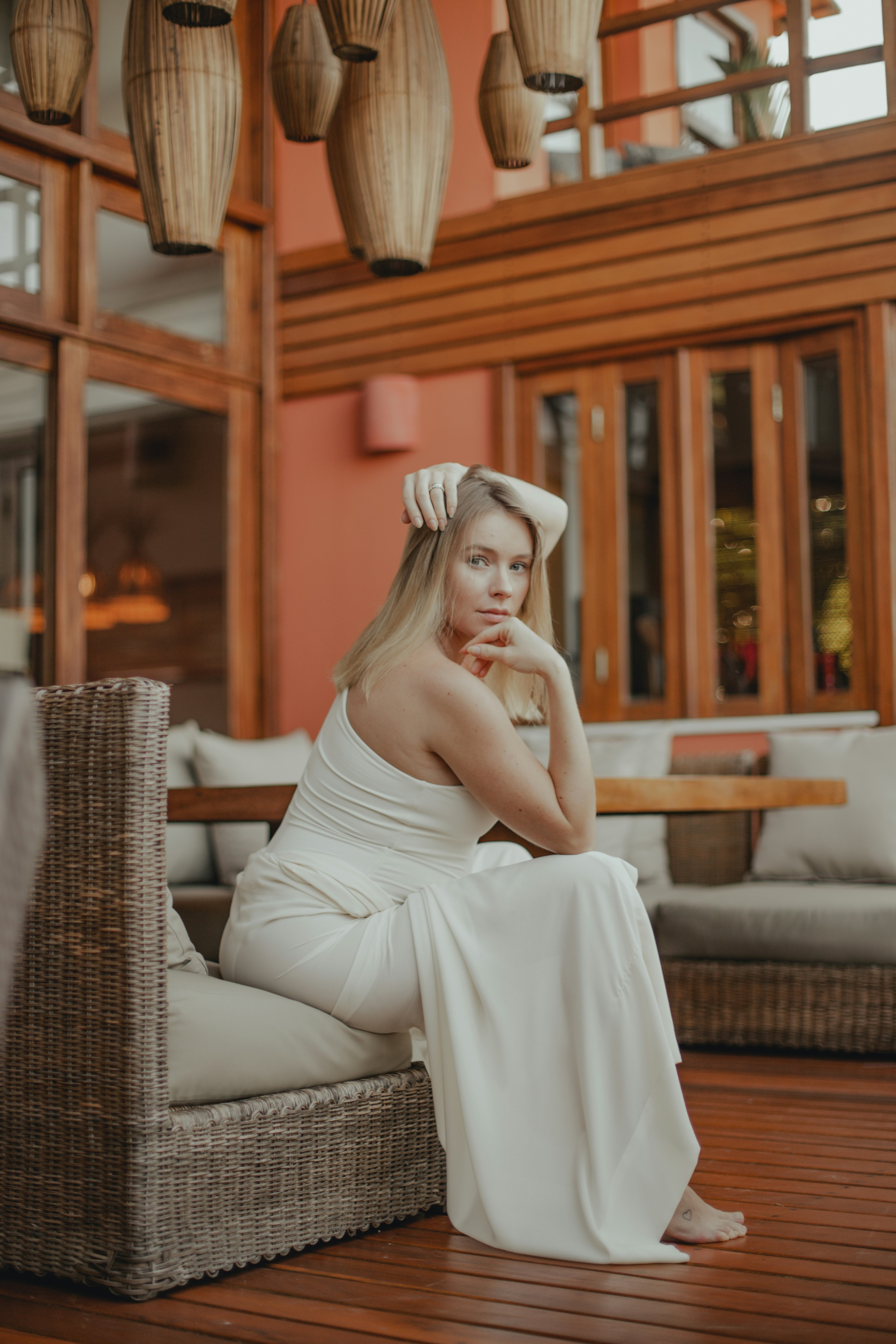 woman in white tube dress sitting on brown wicker armchair