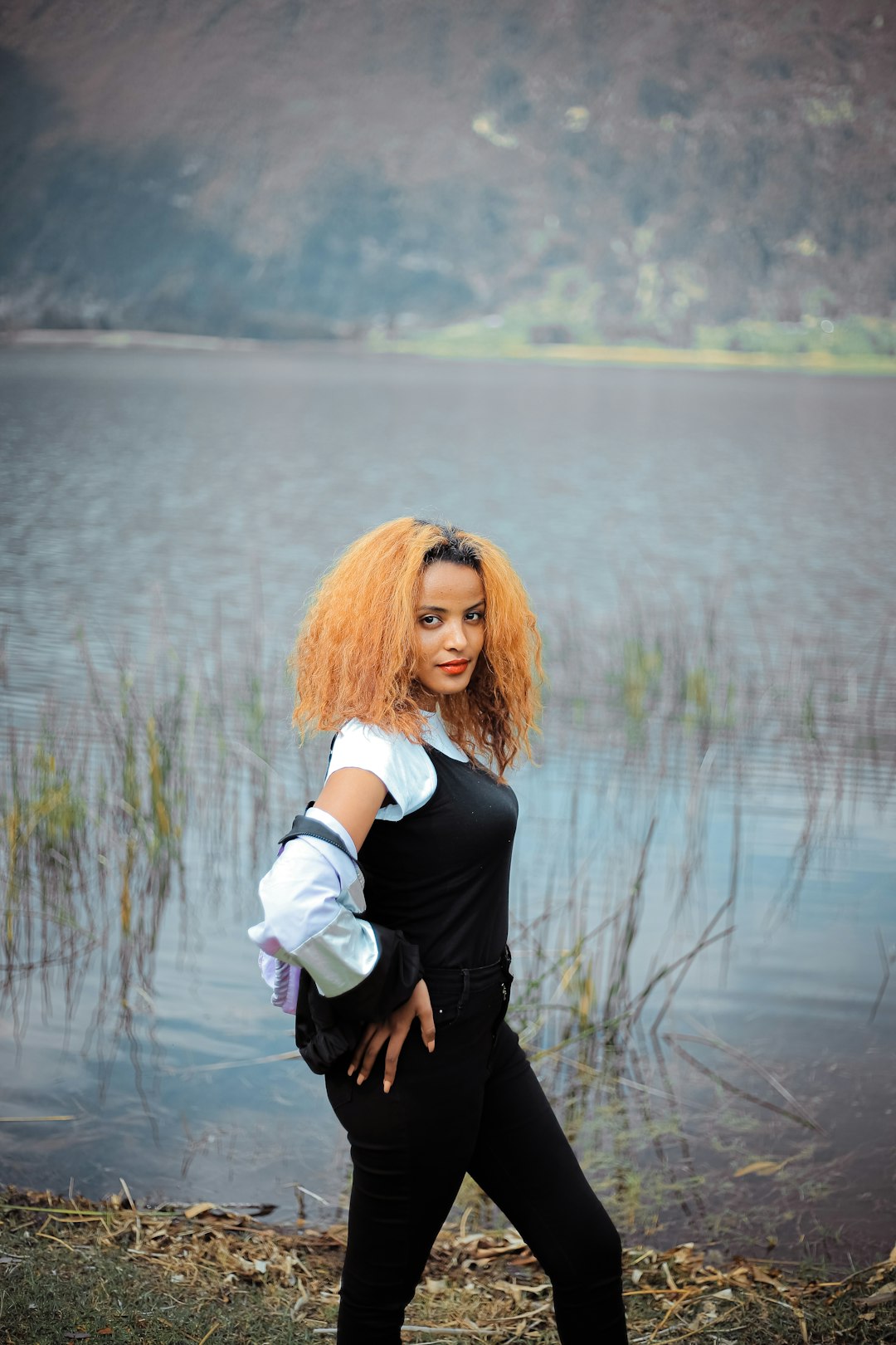 woman in black blazer holding white cup standing near body of water during daytime