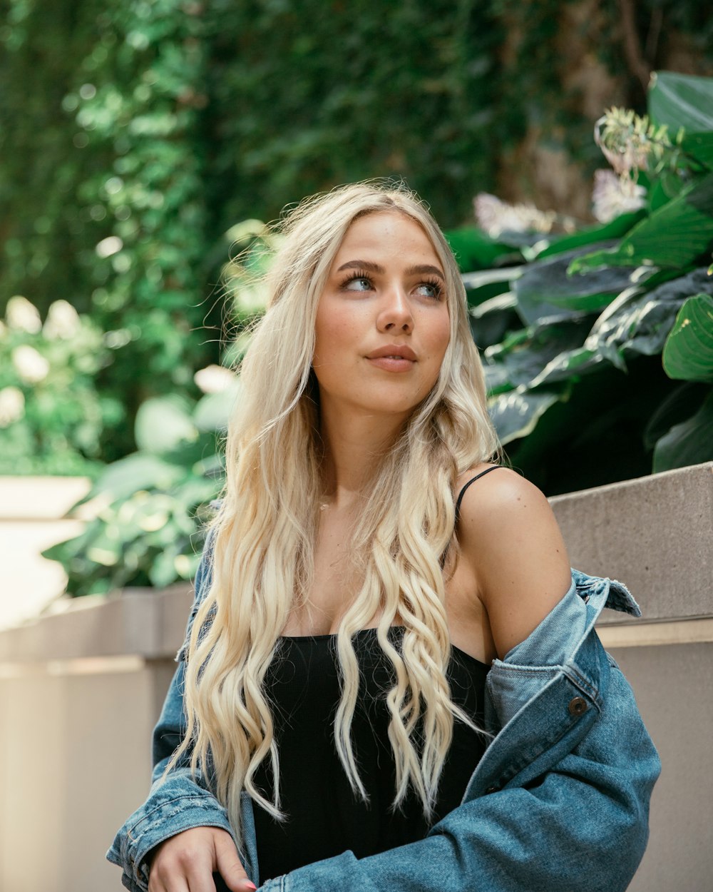 Femme en veste en jean bleue assise sur un banc en bois marron