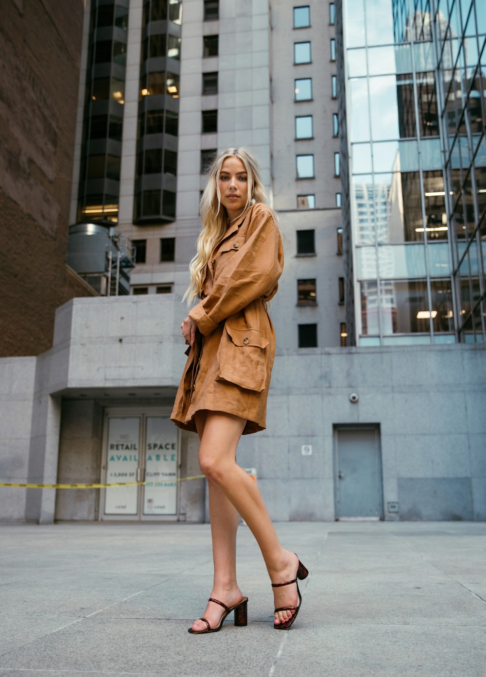 woman in brown coat standing on gray concrete floor during daytime