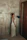 A woman in a simple, elegant beige dress from Synk Clo standing in a bright, clean room with natural light.
