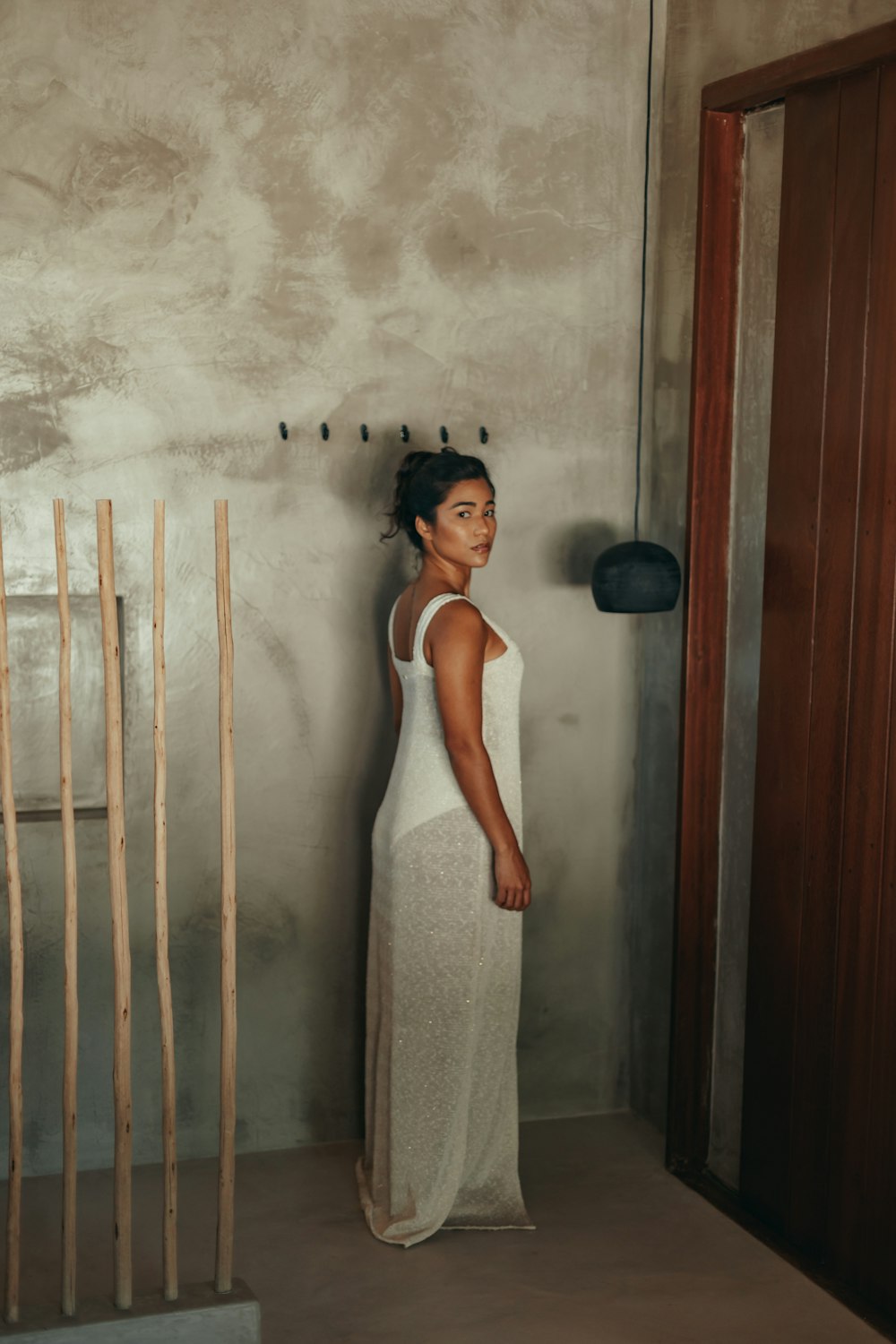 woman in white tank dress standing beside white wall