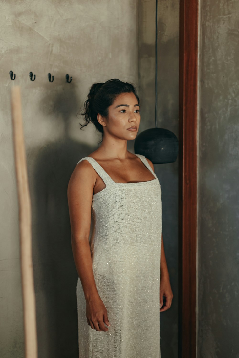 woman in white tank top standing beside brown wooden door