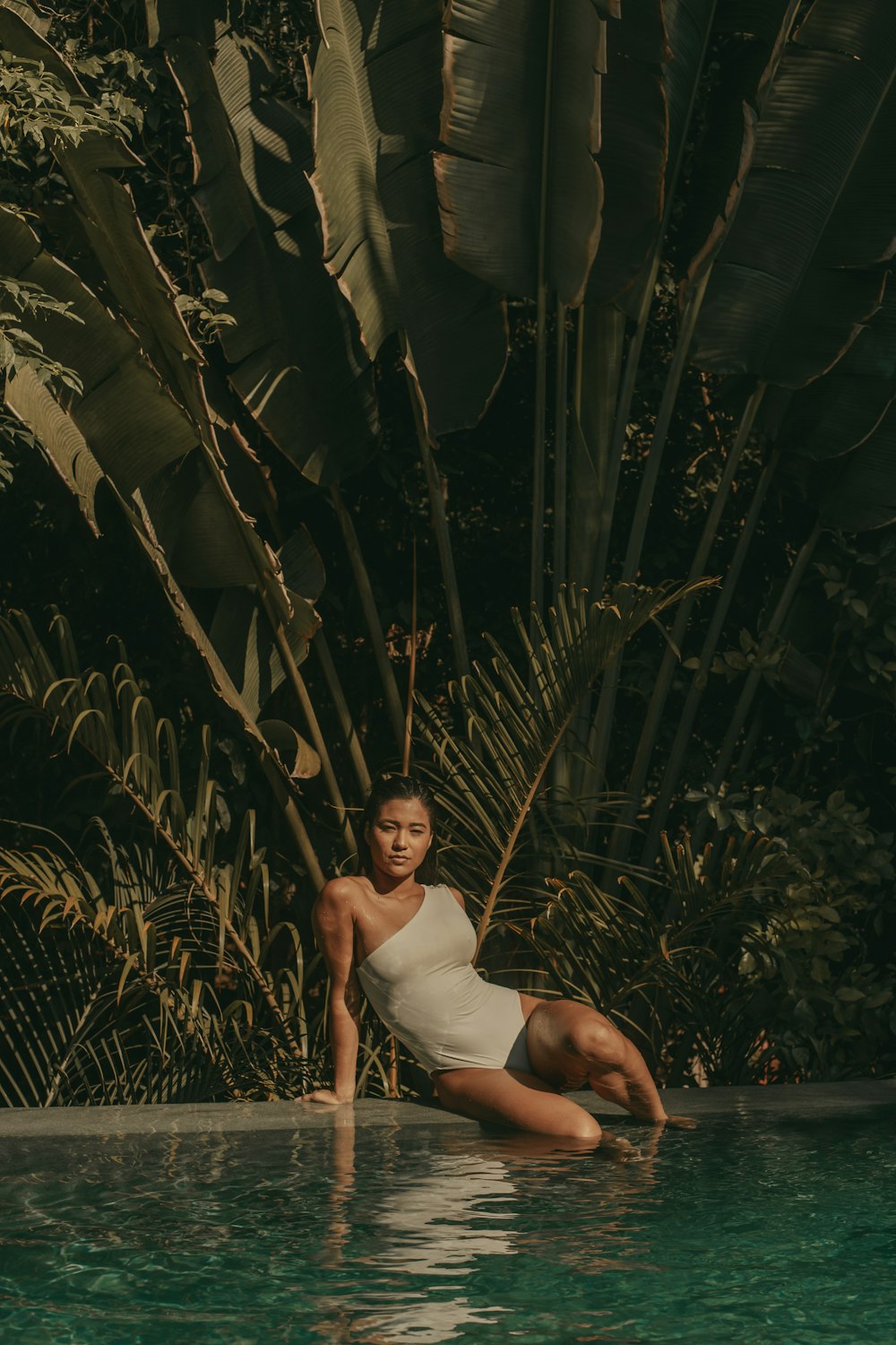 woman in white tank top sitting on green plant