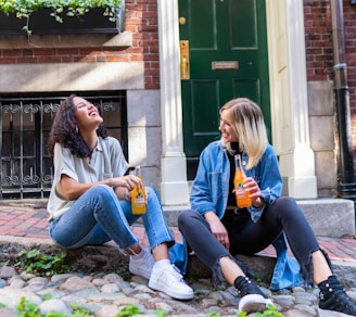 2 women sitting on green grass lawn during daytime