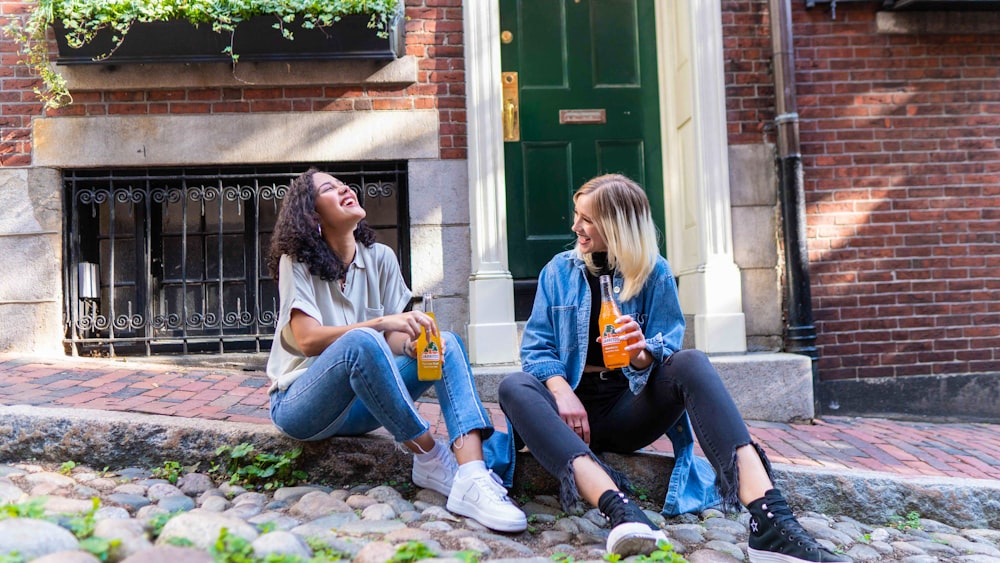 2 donne che si siedono sul prato dell'erba verde durante il giorno