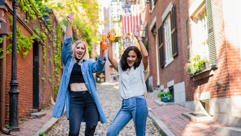 2 women standing on brown brick floor during daytime