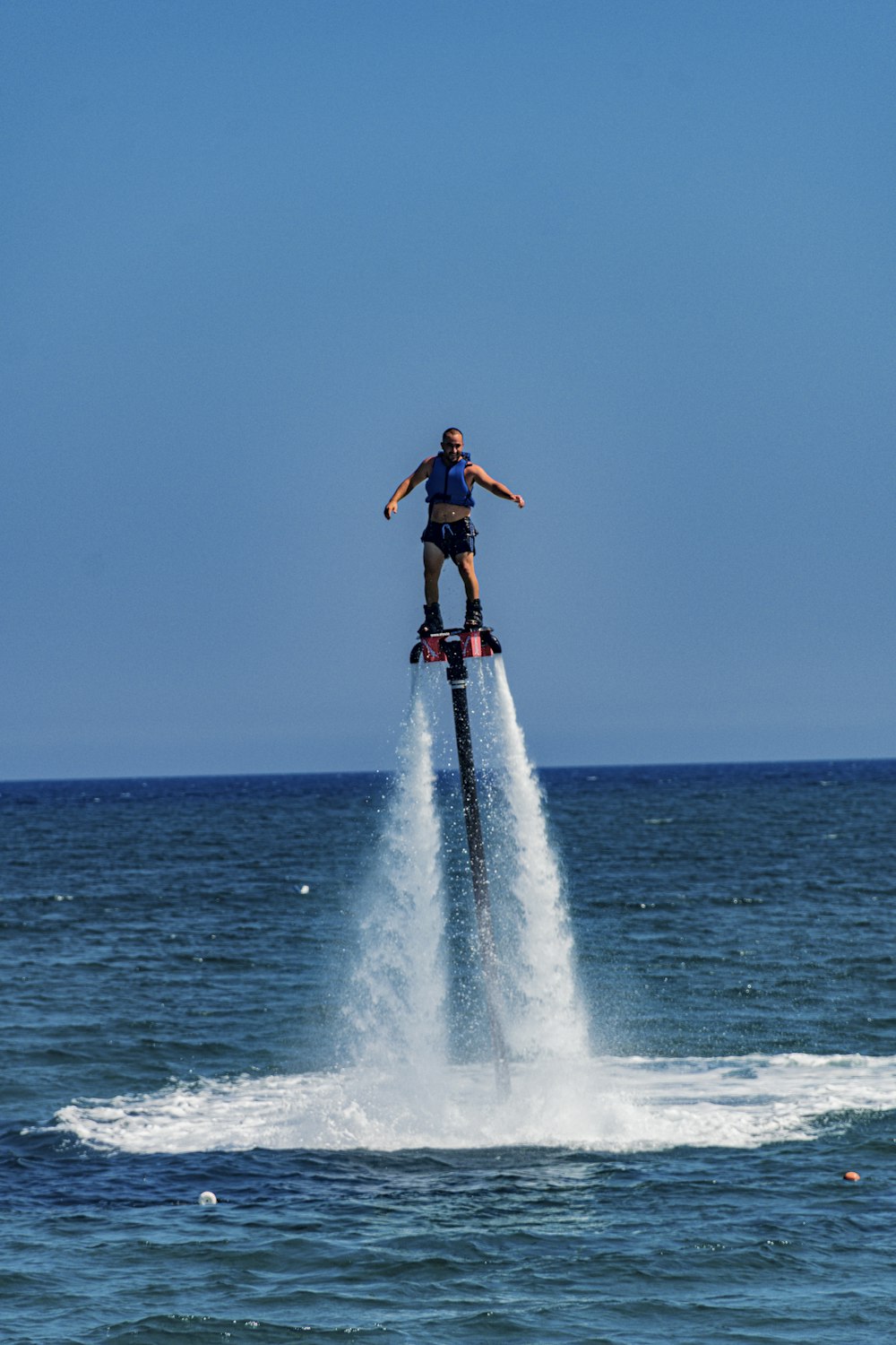 woman in black tank top and blue denim jeans standing on white surfboard on sea waves