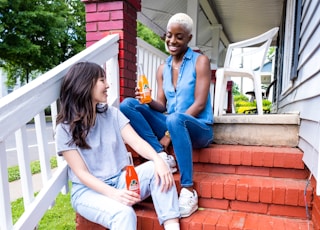 man and woman sitting on red concrete stairs